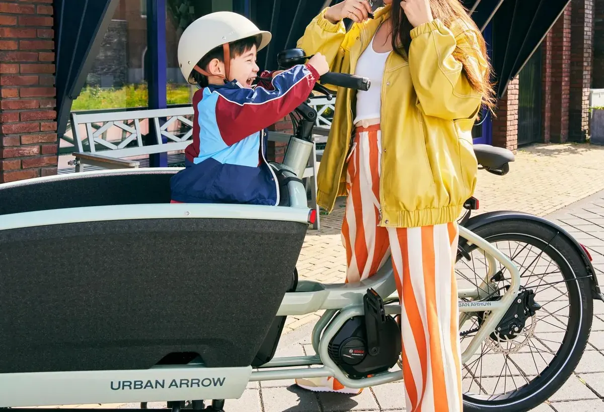 Kind met helm in de bak van een Urban Arrow